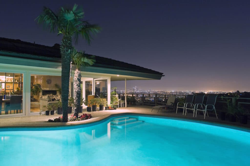 backyard pool installed by professional pool builder overlooking cityscape at night